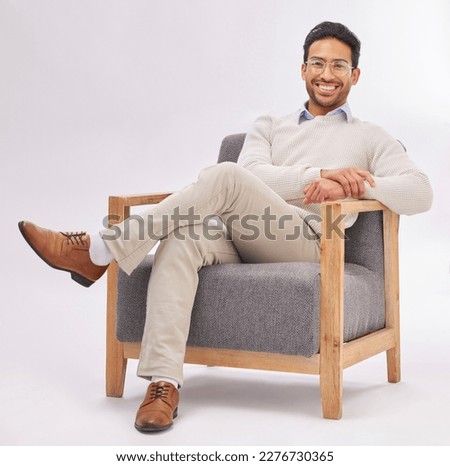 Confident, chair and portrait of entrepreneur sitting happy with a smile and crossed legs isolated in studio white background. Gentleman, relax and professional or proud male employee or business man