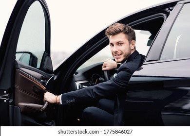 Confident Chauffeur. Guy In Suit Sitting In Driver's Seat, Getting In His Car At Downtown Area, Closing The Door