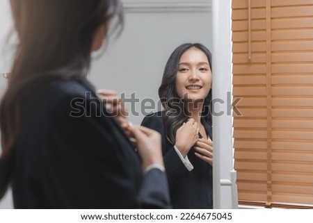 Confident, cheer up asian young woman standing in suit formal, getting dress for work looking at mirror at home before job interview of change career, recruitment employee or staff in company.