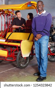 Confident cheerful glad   smiling African-American man recommending traveling with rickshaw
