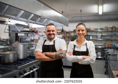 Confident chef and cook standing with arms crossed and looking at camera in commercial kitchen. - Shutterstock ID 2107623101