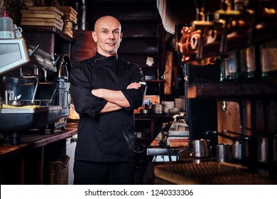 Confident chef posing with his arms crossed and looking at a camera in restaurant kitchen. - Powered by Shutterstock