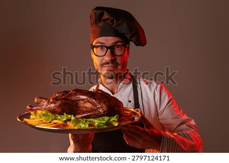 Confident chef serving a roasted duck on a platter with citrus garnish. Fine dining, festive menu and professional culinary service concept.