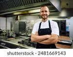 Confident chef standing with crossed arms in the kitchen at restaurant and looking at camera. 