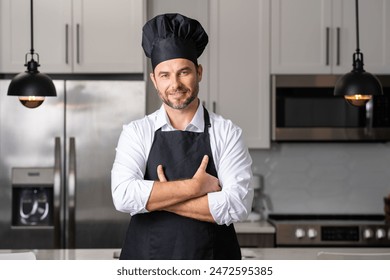 Confident chef wearing glasses and a black hat posing with arms crossed in a bright, modern kitchen. - Powered by Shutterstock