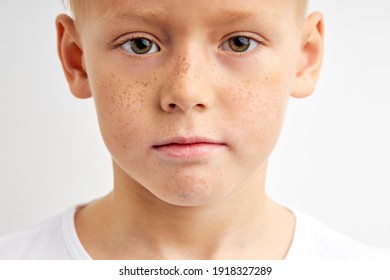 Confident Child With Freckles And Big Green Eyes Looking In Camera With Serious Expression, Caucasian Kid Boy Isolated Over White Studio Background