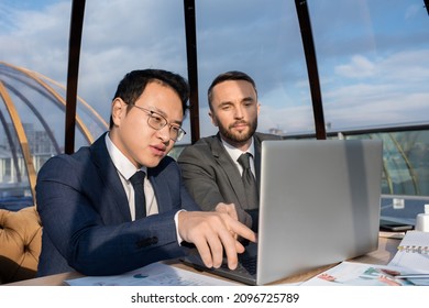 Confident Chinese Businessman Pointing At Screen Of Laptop During Discussion Of Online Data Or Document