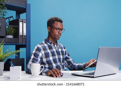 Confident Company Employee Using Work Computer To Analyze Accounting Documentation. Serious Firm Project Manager Sitting At Desk In Modern Office While Using Laptop To Develop Marketing Strategy.