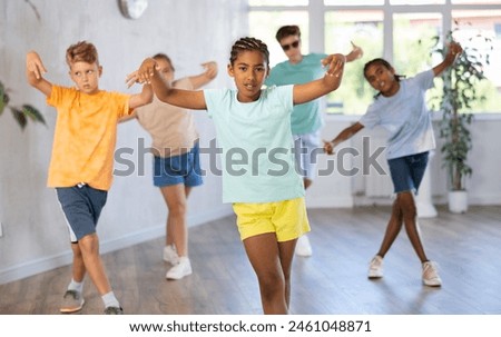 Confident dark-skinned tween girl krumper posing during workout in group dance class for children..