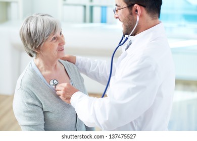 Confident Doctor Examining His Senior Patient In Hospital