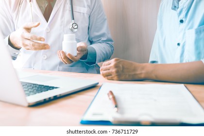 Confident doctor man holding a pill bottle while talking with a senior patient and reviewing his medication at office room. - Powered by Shutterstock