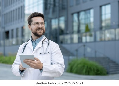 Confident doctor in white coat holding digital tablet and smiling outside modern office building. Professional appearance with stethoscope around neck. Represents medical expertise - Powered by Shutterstock