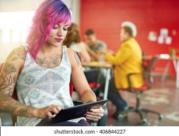 Confident And Edgy Female Designer Working On A Digital Tablet In Red Creative Office Space