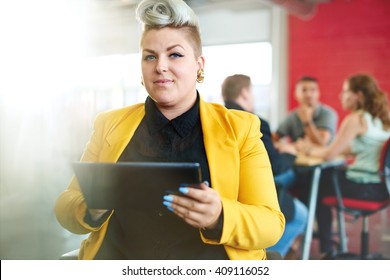 Confident And Edgy Female Designer Working On A Digital Tablet In Red Creative Office Space