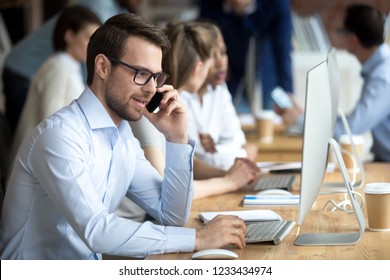 Confident employee talking, consulting by phone with client, sitting at workplace, customer, office worker using computer, looking at monitor screen, searching information - Shutterstock ID 1233434974
