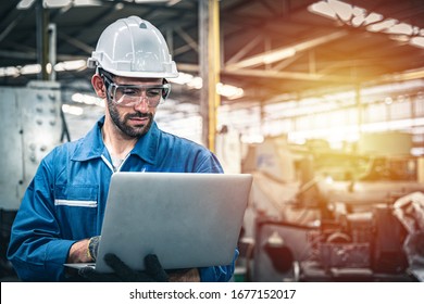 Confident engineer in blue jumpsuit holding laptop computer in a warehouse. - Powered by Shutterstock