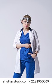 Confident ENT Doctor Wearing Surgical Headlight Head Light And Protective Glasses. Portrait Of Female Otolaryngologist Or Head And Neck Surgeon On Light Grey Background.