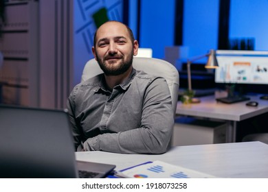 Confident entrepreneur looking confident looking at camera in empy office. Smart businessman sitting at his workplace in the course of late night hours doing his job. - Shutterstock ID 1918073258