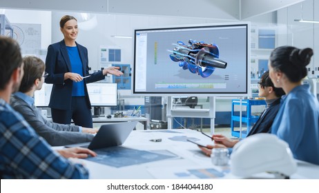 Confident Female Automotive Engineer Reports To Diverse Team Of Specialists, Businesspeople And Investors Sitting At The Conference Table, She Use Interactive TV, Analyze Sustainable Energy Engine