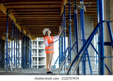 Confident Female builder checks fastenings on a monolithic structure. Construction concept.