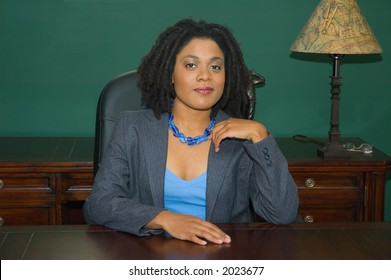 Confident female business executive, sitting behind an impressive desk, in an impressive office.