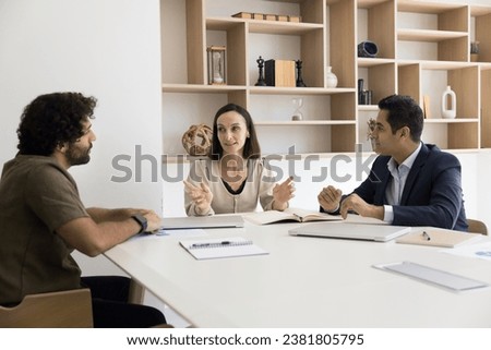 Confident female business leader talking to multiethnic employees at meeting table, giving instructions. Diverse project colleagues brainstorming on work ideas, discussing teamwork strategy