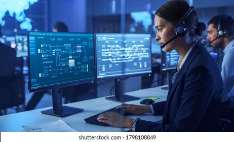 Confident Female Data Scientist Works on Personal Computer Wearing a Headset in Big Infrastructure Control and Monitoring Room. Woman Engineer Works with Network Logics in Office Room with Colleagues. - Shutterstock ID 1798108849