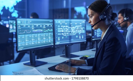 Confident Female Data Scientist Works on Personal Computer Wearing a Headset in Big Infrastructure Control and Monitoring Room. Woman Engineer in a Call Center Office Room with Colleagues. - Shutterstock ID 1798108870