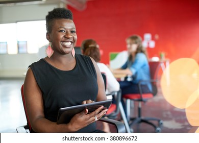 Confident Female Designer Working On A Digital Tablet In Red Creative Office Space