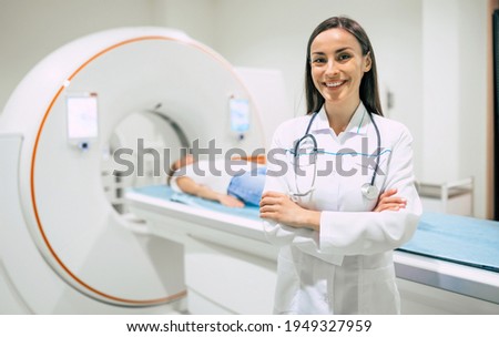 Confident female doctor oncology in magnetic resonance imaging or computed tomography room of a modern hospital.