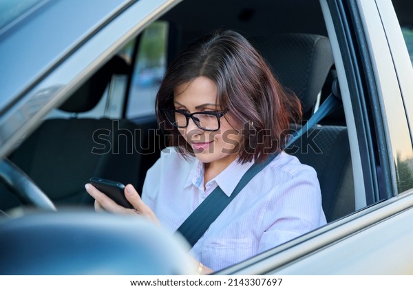 Confident\
female driver with smartphone driving a\
car
