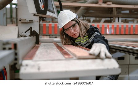 Confident female engineer working in lumber warehouse of hardwood furniture factory inspecting production machine. Serious female technician, carpenter busy working with tool in woodwork manufacturing - Powered by Shutterstock