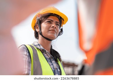 Confident female Indian engineer wearing protective helmet and vest working in factory making precast concrete wall for real estate housing. - Powered by Shutterstock