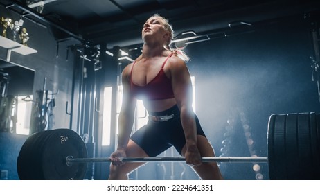 A Confident Female Powerlifter Lifts a Heavy Barbell with Success. A Muscular Woman Empowered By her Determination is Working Out and Training with Weights Exercises. Medium Shot - Powered by Shutterstock