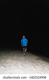 Confident Fit Young African Sports Man Wearing Windbreaker Exercising Outdoors At Night Time, Running At The Beach