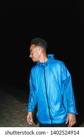 Confident Fit Young African Sports Man Wearing Windbreaker Exercising Outdoors At Night Time, Running At The Beach