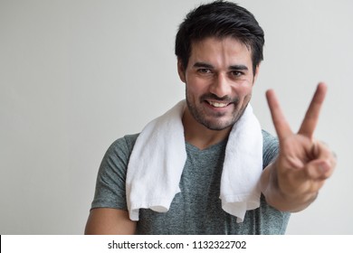 confident fitness man pointing up two fingers; portrait of happy, healthy, confident fitness asian man pointing number two fingers sign, v for victory hand gesture; asian north indian adult man model