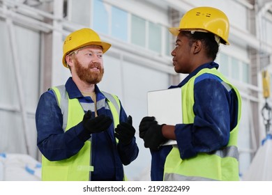 Confident Foreman In Workwear, Gloves And Safety Helmet Consulting Young African American Female Subordinate At Meeting