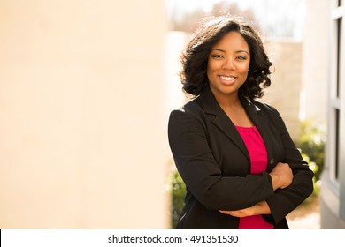 Confident friendly black business woman standing with folded arms.