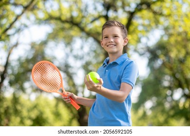 Confident friendly boy with racket and tennis ball