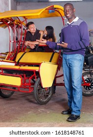 Confident glad  positive smiling African-American man recommending traveling with rickshaw