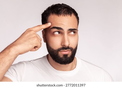 Confident guy pointing at smooth forehead skin after treatment and anti wrinkle beauty procedure wearing white t-shirt isolated over gray background