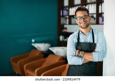 Confident Hair Salon Owner Standing With His Arms Crossed At The Salon And Looking At Camera.