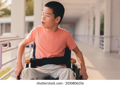 Confident Handicapped Teenager Boy On Wheelchair With Happy Face On Walk Way In Hospital, Smart Disabled Kid Activity To See A Doctor And Push Wheel By Himself,Mental Health Of Diverse People Concept.