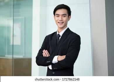 Confident handsome business man in black suit standing in office, young asian man smilling - Powered by Shutterstock