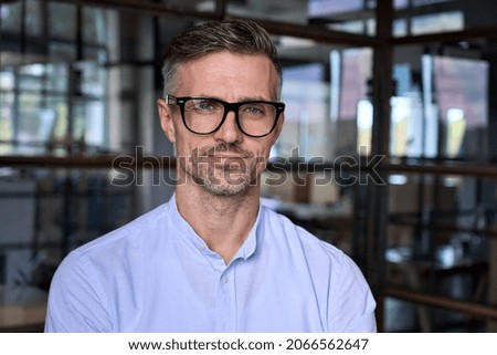 Confident handsome mature businessman professional financial advisor, executive leader, manager, male lawyer or man entrepreneur in glasses standing in office posing for headshot business portrait.