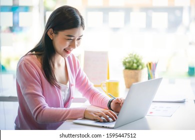 Confident Happiness Young Woman Working On Laptop Or Notebook In Her Office. Beautiful Freelancer Woman Working Online At Her Home. Beauty Asian Business Woman Concept.