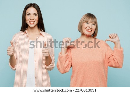 Confident happy elder parent mom with young adult daughter two women together wear casual clothes point on herself show thumb up like gesture isolated on plain blue cyan background. Family day concept