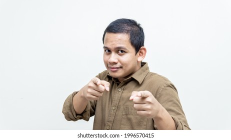 Confident And Happy Face Expression Of Young Asian Malay Man Pointing Finger At The Camera And People In Front. Choosing You Concept.