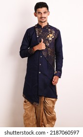 Confident Happy Young Indian Man Wearing Salwar Do Thumbs Up Pose While Standing In Front Of White Wall. All The Best. Ethnic Or Traditional Outfit Kurta Cloths. Male Fashion Model In Sherwani Dress.